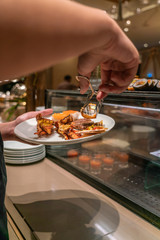 Obraz na płótnie Canvas Vertical photo of young man choosing food in the hotel buffet
