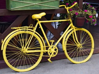 Fototapeta na wymiar Yellow bicycle with a basket of flowers outdoors. Retro decor