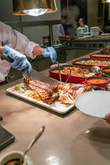 Vertical photo of chef cooking grilled fish in the buffet restaurant