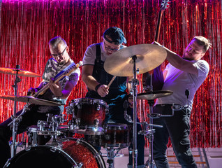 Three men play musical instruments