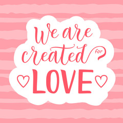 Modern calligraphy lettering of We are created for love in pink on white pink striped background decorated with hearts for decoration, poster, banner, valentine, valentines day, sticker, postcard