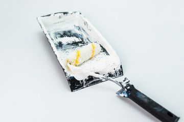 Used, dirty paint roller lies on a black paint tray. Isolated on a white background with a clipping path.