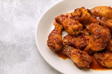 chicken legs with hot sauce on a white plate. restaurant menu. place for text and copypast