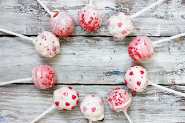 Red velvet cake pops covered in white chocolate decorated with red and pink sugar sprinkles, sweet treats for valentine day