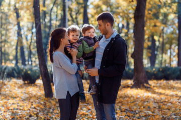 Natural pictures of a happy family of four having fun outsiade on a sunny autumn day. Togetherness and happiness concept