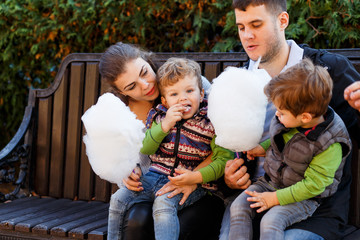 Natural photos of happy family resting in the park eating sugar floss and having fun. Love and...