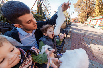 Natural photos of happy family resting in the park eating sugar floss and having fun. Love and...