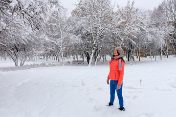Shot of a happy and stylish beautiful woman in a bright coral jacket and blue jeans, smiling, enjoying the winter day.
