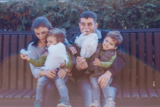 Natural photos of happy family resting in the park eating sugar floss and having fun. Love and togetherness concept