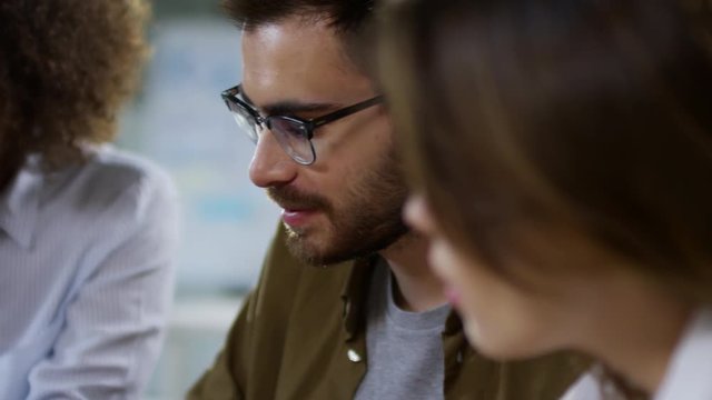 Close up faces of group of young designers of different ethnicities talking to each other and smiling while choosing colors together