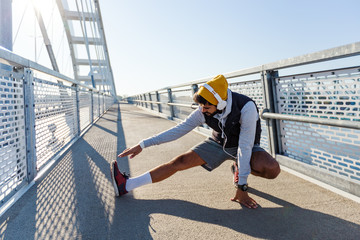 Attractive sporty man stretching his leg