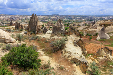 A dirt road meanders between conical peaks of rocks, ancient caves against the backdrop of the mountain landscape of the valley in Cappadocia