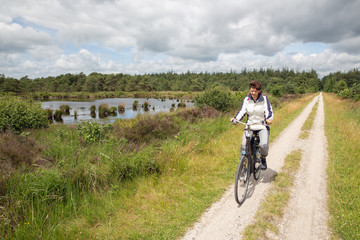 Obraz premium Biking woman in Dutch national park with forest and wetlands