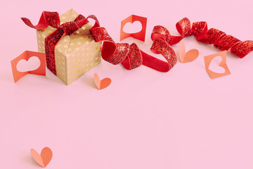 Gift box with red ribbon and red paper hearts on pink background. Valentine's day, love, holiday present concept