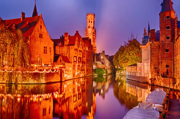 View of river canal and Belfort (Belfry) tower at twilight from Rozenhoedkaai,famous boat tour point in Bruges, Belgium.