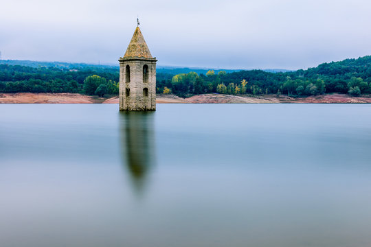 Reflections of the old church tower emerged from the water, at Sau Reservoir (Catalonia, Spain).