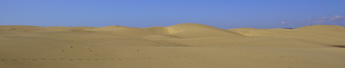 The Maspalomas Dunes (Spanish: Dunas de Maspalomas), against a clear blue sky.