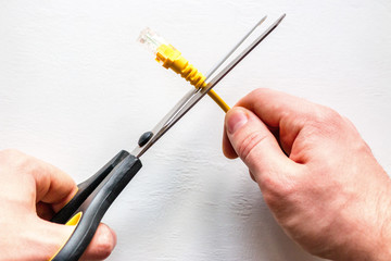 man cuts yellow network internet cable on white background