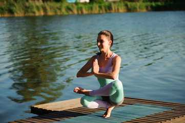 Young healthy woman practicing yoga at sunset