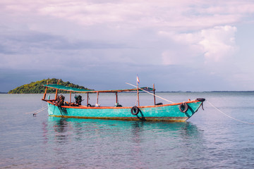 Fototapeta na wymiar Blue wooden fishing boats in calm tropical turquoise water near Rabbit Island in Cambodia