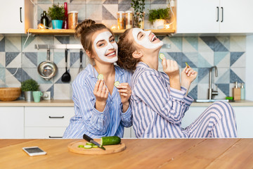 Portrait of two best friends laughing and having fun on kitchen with nice interior. Cheerful models...