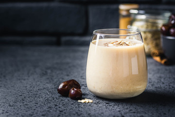 Oatmeal dates cinnamon smoothie on dark background. Selective focus, space for text.