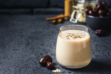 Oatmeal dates cinnamon smoothie on dark background. Selective focus, space for text.