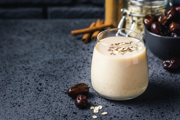 Oatmeal dates cinnamon smoothie on dark background. Selective focus, space for text.