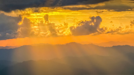 sunset at Nern Chang Suek, beautiful high mountains with dark clouds and yellow sun rays in the sky background, Nern Chang Suek View Point, Thong Pha Phum, Kanchanaburi, Thailand.