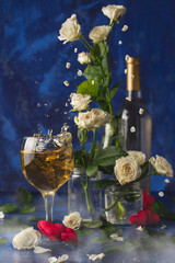 Valentines day.Splash of white wine. Romantic evening. Wine, a bunch of white roses and red hearts with smokeon a blue background. Holiday of lovers. A delicious alcoholic drink for two people.Picture