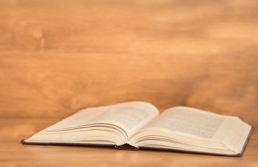 Open book on wooden background.