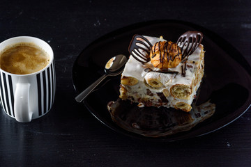Tiramisu and a cup of coffee on a black background.