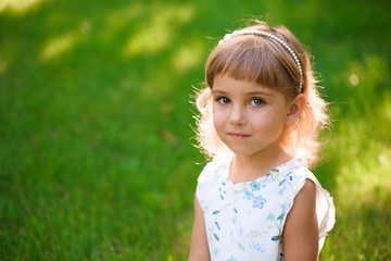 Portrait of a beautiful young little girl in summer park