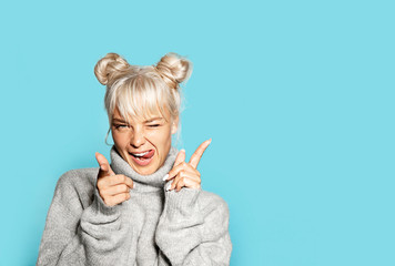 Portrait of beautiful blonde girl wearing cozy grey sweater and making faces. Pretty model in...