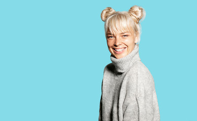 Portrait of young charming woman feeling happy in trendy warm knitted sweater. Sweet smiling blonde...