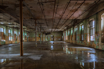 Shabby interior with windows and reflections in  the puddles on the floor inside the abandoned factory building