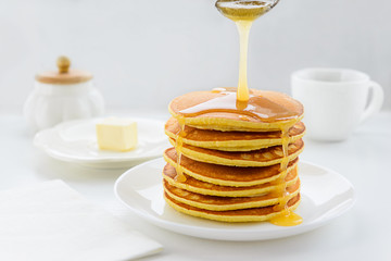 Pancakes with honey on a white wooden table