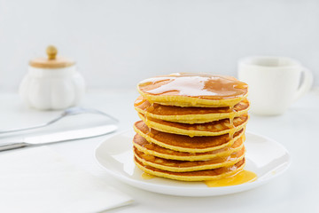 Pancakes with honey on a white wooden table