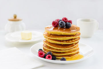 American pancakes with berries and honey on a wooden table