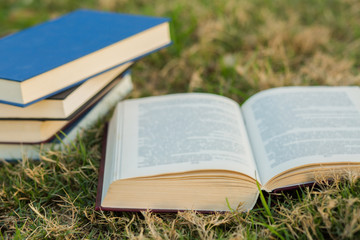 Pile of closed book with open book outdoors on wooden background