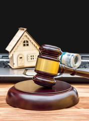 Real estate law and auction concept. Judge's gavel with model of house, money and laptop on the table.