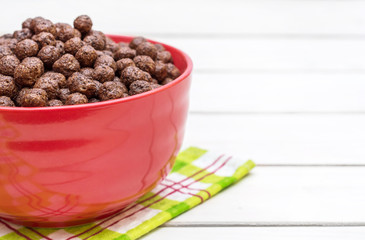 Red bowl with chocolate corn balls on kitchen towel. Space for text.