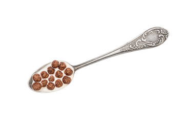 Spoon with chocolate corn balls in milk on white background.