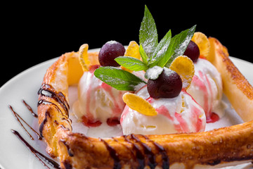 Ice cream dessert with puff pastry, with grapes and mint, on a white plate, on a black background