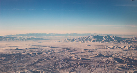 Naklejka na ściany i meble The sky with clouds and mountains in snow. Photo taken from an airplane.