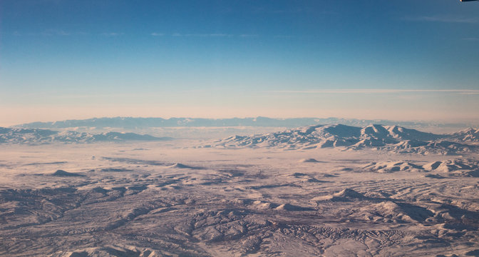 The sky with clouds and mountains in snow. Photo taken from an airplane.