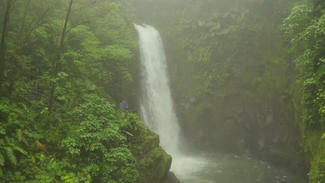 Aerial: Taking Picture of a Couple on Viewing Platform in front of Waterfall