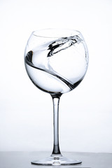 Water splashing in the luxury wine glass close up. Concept of good healthy and refreshment.