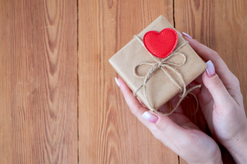 Woman holding a gift box in a gesture of giving.