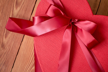 Gift or gift box with a red bow of a ribbon in the shape of a heart on a rustic background for Valentines Day.